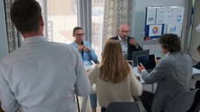 Serious office team sits around the table preparing for business meeting. Colleagues with laptops and charts focus on strategy and corporate discussion in professional workplace setting. - Powered by Shutterstock - Get 15% off with code: PIKWIZARD15