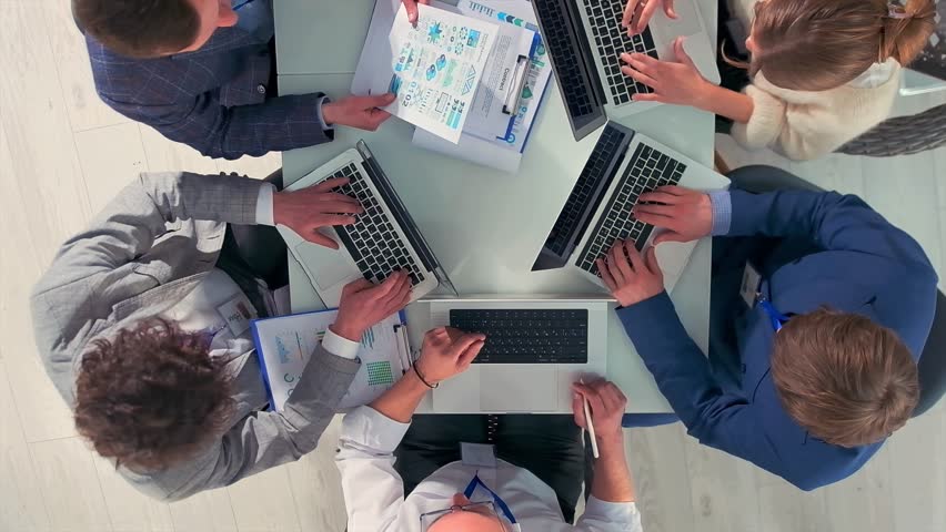 leadership analyzes performance metrics together, executive team engages in strategic planning with visual data, bright workspace hosts collaborative session analyzing charts and discussing growth