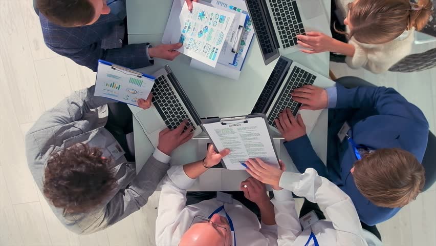 leadership analyzes performance metrics together, executive team engages in strategic planning with visual data, bright workspace hosts collaborative session analyzing charts and discussing growth