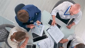 Overhead view of colleagues exchanging financial graphs and printed statistics working on laptops. Business team of consultants and investors discusses market performance and investment strategy. - Powered by Shutterstock - Get 15% off with code: PIKWIZARD15
