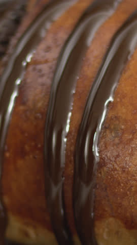 Dark chocolate fluid cascades over a French cake, revealing a rich chocolate filling, highlighting glossy textures, decadent layers, and cinematic dessert appeal for gourmet visual content.