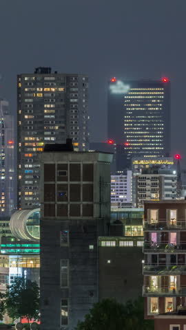 Aerial timelapse of modern buildings in Rotterdam city center, The Netherlands. Illuminated towers and skyscrapers in the financial district, with glowing windows creating a vibrant nighttime skyline