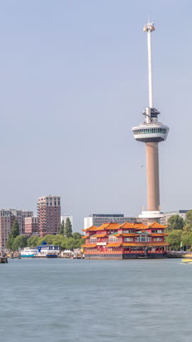 Rotterdam cityscape timelapse with Euromast observation tower and a tourist boat on Nieuwe Maas River. Waterfront features modern skyscrapers, a floating Chinese restaurant and a scenic harbor view