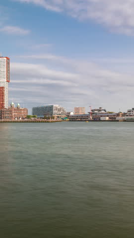 Panorama showing Rotterdam skyline timelapse from Nieuwe Maas River bank to Wilhelminapier and Kop van Zuid. Modern skyscrapers, ship terminal and Erasmus Bridge, waterfront with boats passing by