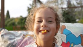 Close-up of a cheerful young girl with blonde curly hair smiling widely and making a silly face with two small pieces of french fry held between her lips like teeth - Powered by Shutterstock - Get 15% off with code: PIKWIZARD15