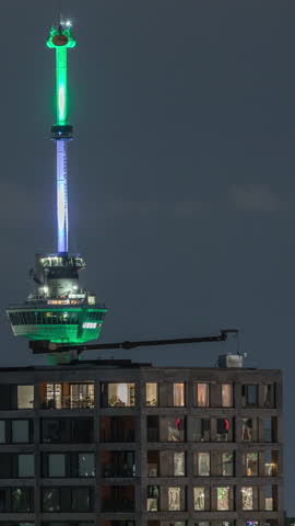 Rotterdam night cityscape timelapse with Euromast observation tower and glowing windows in high-rise buildings. Waterfront features illuminated modern skyscrapers and a scenic harbor view