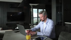 Young businessman sitting at a table at home working on a laptop and writing notes down on a notepad - Powered by Shutterstock - Get 15% off with code: PIKWIZARD15
