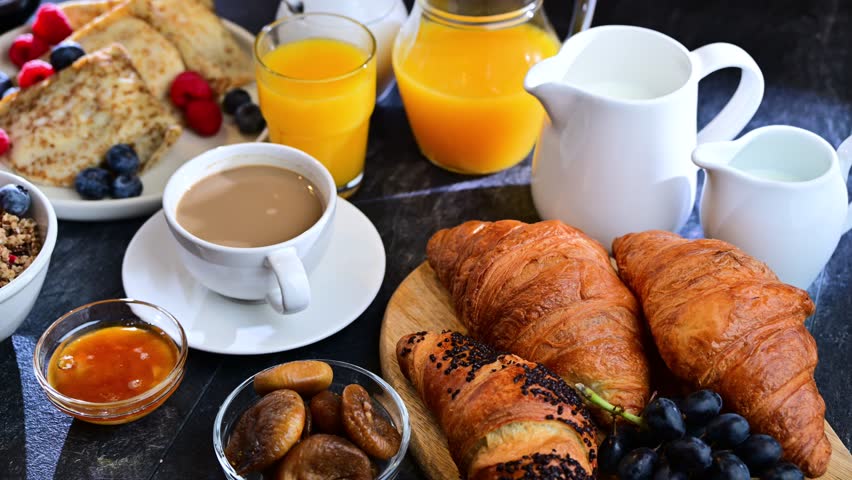 Breakfast served with coffee, orange juice, scrambled eggs, cereals, pancakes and croissants.
