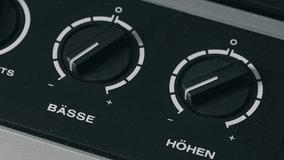 Macro shot of a hand adjusting bass and treble control knobs on a vintage German audio device, turning black dials labeled Basse and Hohen to equalize sound on retro stereo equipment. - Powered by Shutterstock - Get 15% off with code: PIKWIZARD15