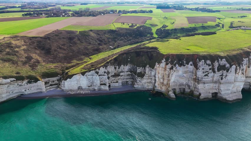 Aerial drone view of picturesque coastal limestone cliffs and the English Channel town of Etretat, France. High quality 4k footage