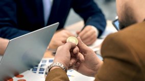 Male hands holding a physical cryptocurrency coin in an office with gadgets and papers, symbolizing digital finance, blockchain, and modern investment. - Powered by Shutterstock - Get 15% off with code: PIKWIZARD15