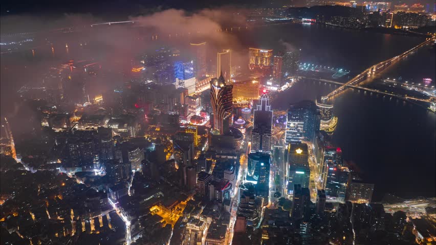 Aerial view of Macau under the night sky, flying above the clouds.