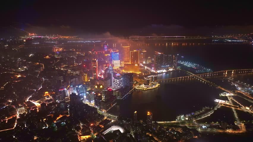 Aerial view of Macau under the night sky, flying above the clouds.