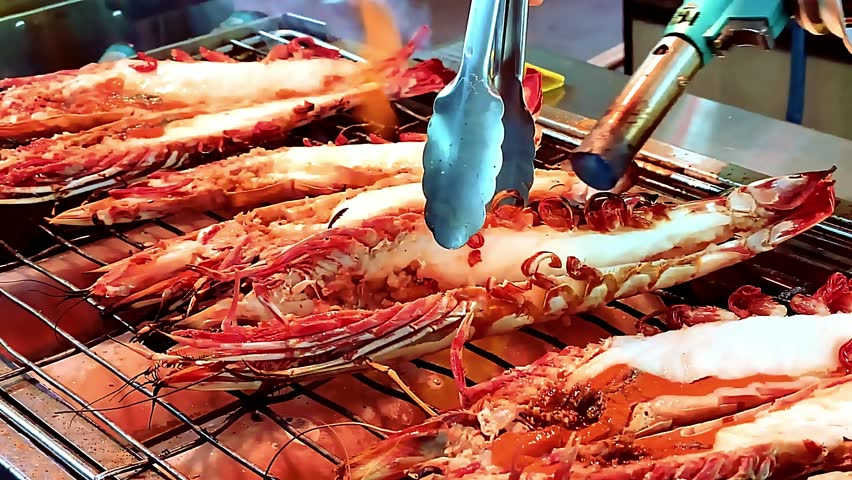 King giant prawns grilled - large juicy prawns barbecued over open flame with smoky butter glaze. The chef grills them to golden perfection, capturing sizzling texture, luxurious seafood delicacy food