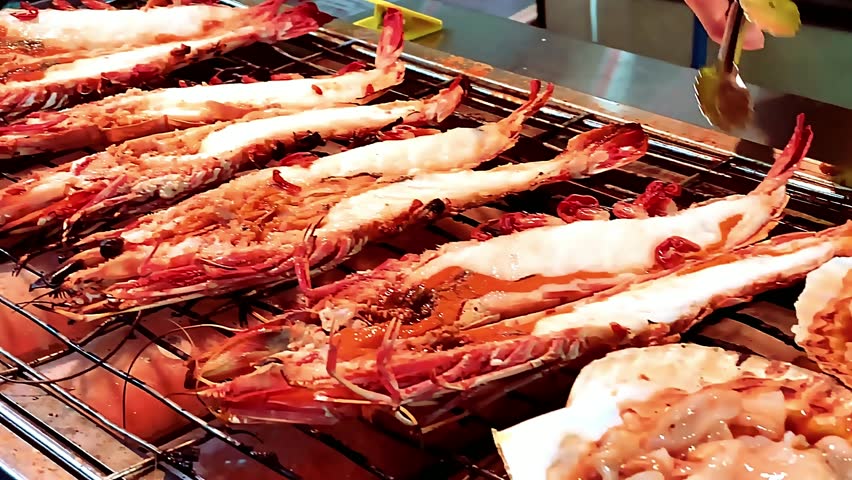 King giant prawns grilled - large juicy prawns barbecued over open flame with smoky butter glaze. The chef grills them to golden perfection, capturing sizzling texture, luxurious seafood delicacy food