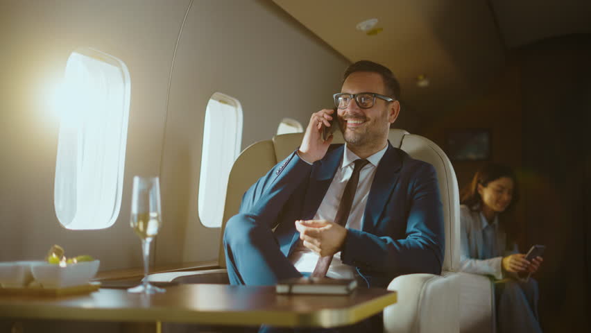Confident and successful businessman talking on his smartphone while traveling in a luxurious private jet, enjoying a first-class flight and closing deals while flying to his destination - Powered by Shutterstock - Get 15% off with code: PIKWIZARD15