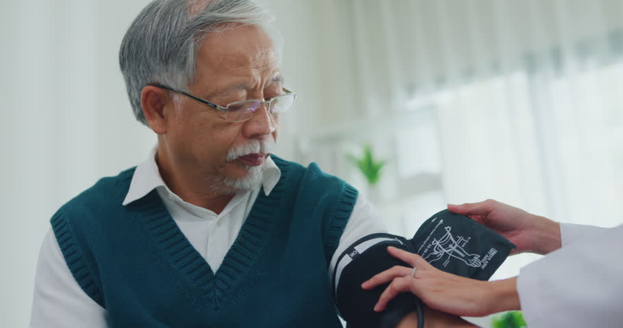 Young Asia female doctor with old man patient using blood pressure consultation or cardiology wellness or hypertension, checkup or healthcare on sofa in health clinic office. Medical worker for care.