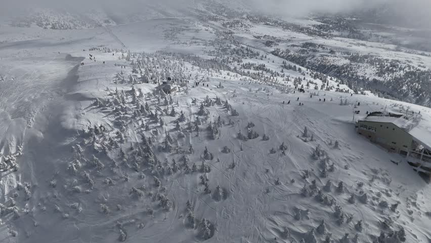 Aerial panorama above Mount Hakkoda cable car station, and tourists playing in Juhyo forests (ice trees, snow monsters) on the snowy mountainside, in Towada-Hachimantai National Park, Aomori, Japan