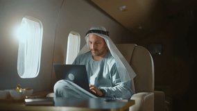 Wealthy arab businessman in traditional clothing working on a laptop computer while traveling in a first-class cabin on a private jet, demonstrating a luxurious and successful lifestyle - Powered by Shutterstock - Get 15% off with code: PIKWIZARD15
