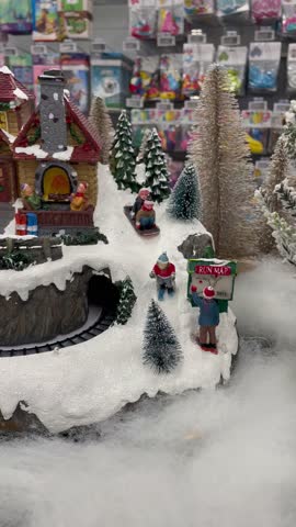 Vertical screen miniature christmas village in supermarket snowy house trees and tiny people skiing joyful festive atmosphere cozy winter scene full of light warmth and holiday spirit