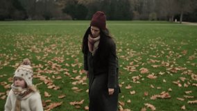 Young woman in coat, scarf and hat walking with her daughter in city park during windy autumn day. Seasonal lifestyle outdoors - Powered by Shutterstock - Get 15% off with code: PIKWIZARD15