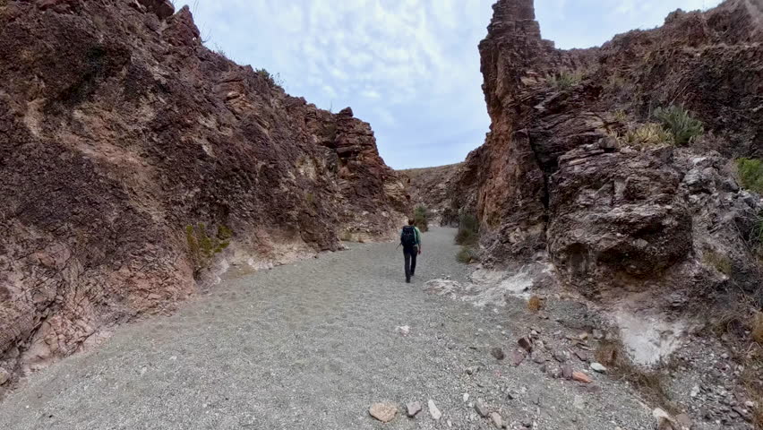 Man Walks through Slot Canyon Toward Arch in Big Bend