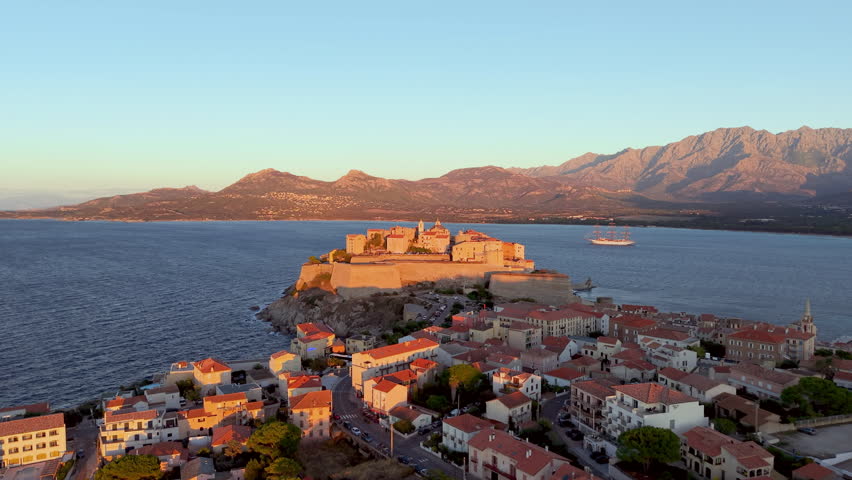 Aerial view of calvi citadel at sunrise with serene waters. Fortress with marina. Corsica. France