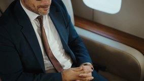 Successful businessman in a suit checking the time on his smartwatch while traveling in a comfortable first-class seat on a private jet, managing his busy schedule during a flight - Powered by Shutterstock - Get 15% off with code: PIKWIZARD15