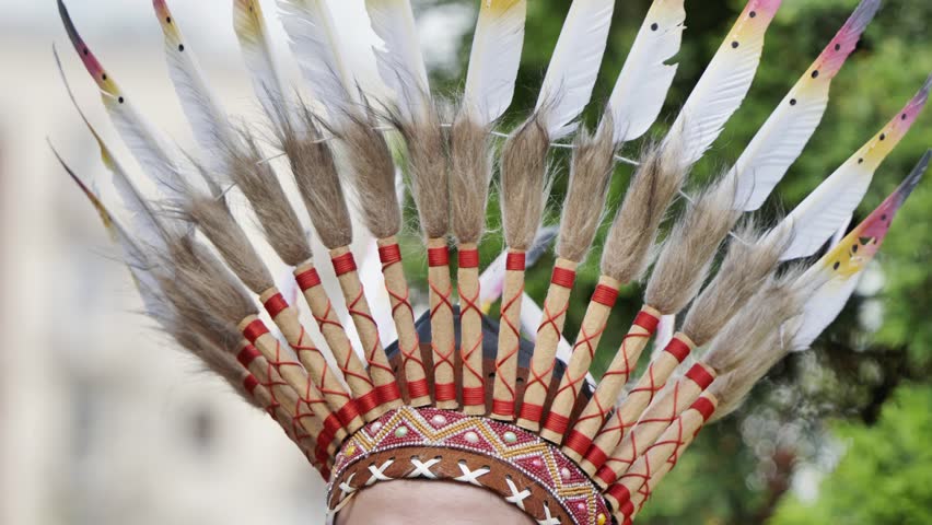Indigenous person wearing traditional headdress with white feathers during Latin American festival