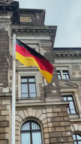 German flag waves proudly in front of historic building in Berlin during early morning hours