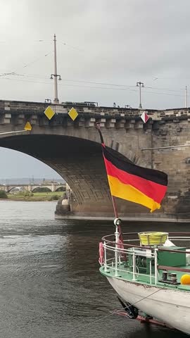 Enjoying a river cruise under a historic bridge with a German flag on display