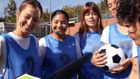 Group of female soccer players smiling and listening to their coach explaining the game strategy on a clipboard before a match, demonstrating teamwork, empowerment, and sportsmanship - Powered by Shutterstock - Get 15% off with code: PIKWIZARD15