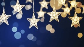A beautiful cinematic animation focusing on transparent, star-shaped lights swaying gently against a soft blue bokeh. Perfect for festive overlays or a charming event intro - Powered by Shutterstock - Get 15% off with code: PIKWIZARD15