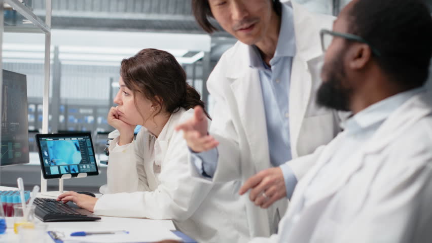 Diagnostic laboratory manager overseeing scientists looking at molecular models on PC. Team leader supervising researchers using bioengineering program on computer in medical lab, camera B - Powered by Shutterstock - Get 15% off with code: PIKWIZARD15