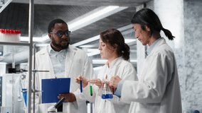 Multiracial chemists using research facility vials filled with indicator solution. Teamworking lab professionals using chemical fluid test tubes for experiments, camera B - Powered by Shutterstock - Get 15% off with code: PIKWIZARD15