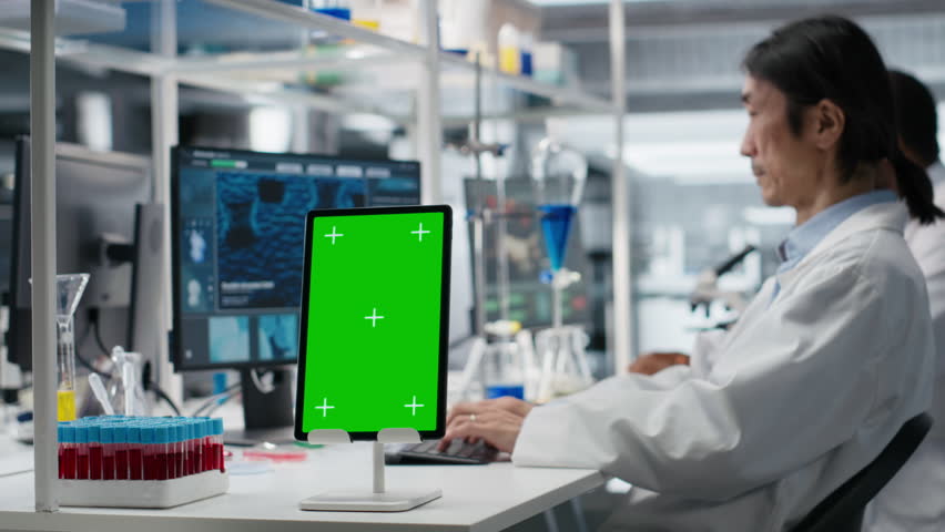 Lab expert at desk using green screen tablet, looking at molecular model, doing research tasks. Asian man using bioengineering program on mockup device in medical lab, camera B - Powered by Shutterstock - Get 15% off with code: PIKWIZARD15