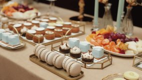 Luxury dessert table with macarons, mini cakes, and fresh fruit platter, elegant catering setup for wedding or celebration, pastel sweets and gold trays creating a sophisticated festive decor - Powered by Shutterstock - Get 15% off with code: PIKWIZARD15