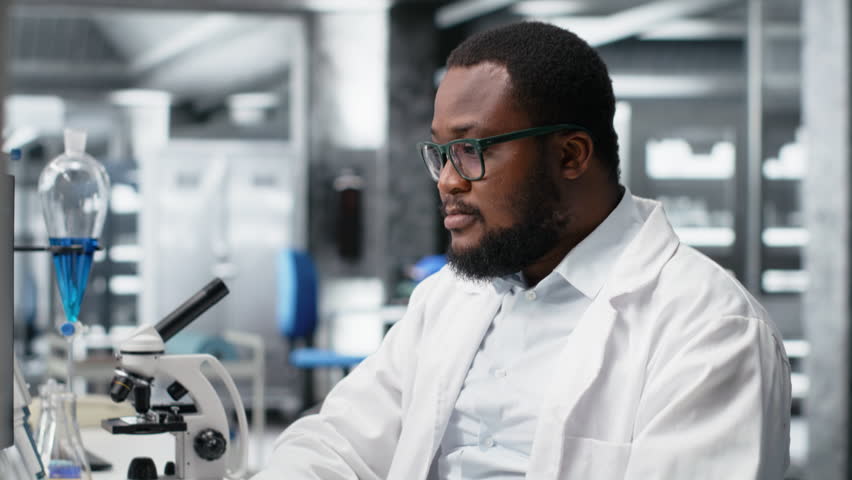 Laboratory worker squinting eyes at computer monitor, struggling to understand DNA data. African american lab expert unable to believe eyes while looking at genetic analysis diagnostics, camera B - Powered by Shutterstock - Get 15% off with code: PIKWIZARD15