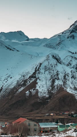 Stepantsminda, Georgia. Winter Night Starry Sky With Glowing Stars Over Peak Of Mount Kazbek Covered With Snow. Beautiful Night Georgian Winter Landscape
