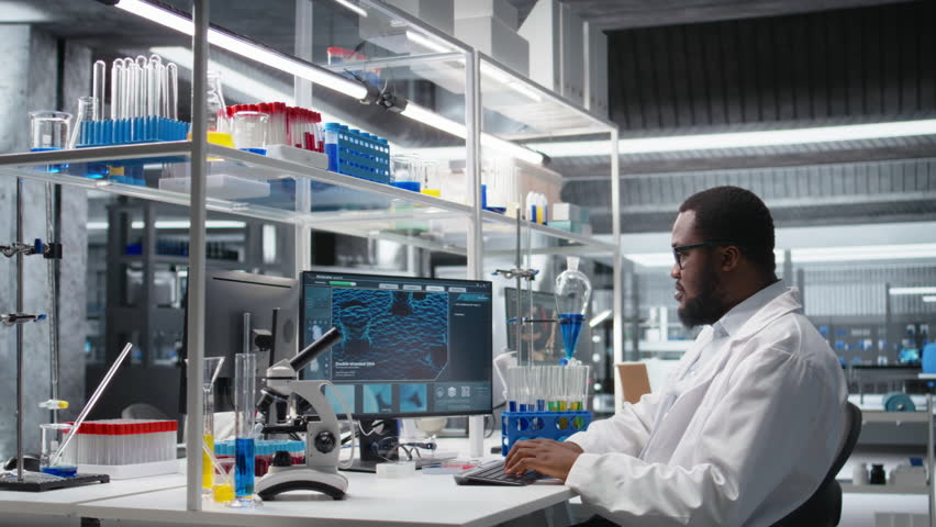 High tech lab technician at desk typing on PC keyboard, looking at molecular model, doing research tasks. African american man using bioengineering program on PC in medical lab, camera A - Powered by Shutterstock - Get 15% off with code: PIKWIZARD15