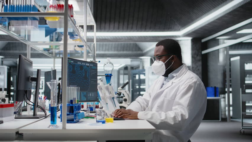 Researcher wearing medical mask in sterile laboratory using computer for DNA data analysis. African amerian man wearing protective face mask using bioinformatics genomics software on PC, camera A - Powered by Shutterstock - Get 15% off with code: PIKWIZARD15