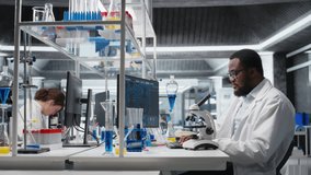 Lab scientist using microscope to evaluate cellular structures. African american man observes specimens through magnification tool at laboratory bench, advancing scientific knowldege, camera A - Powered by Shutterstock - Get 15% off with code: PIKWIZARD15