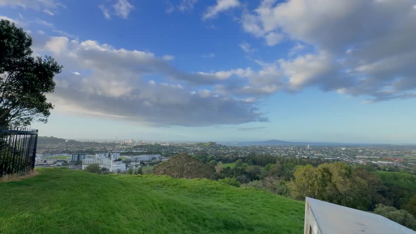 The sun is setting into the horizon at the city. The view is from high ground green mountain in summer time. Beautiful orange sunset view of Auckland city.