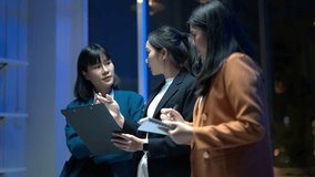 Three women in business attire are standing together and talking. One of them is holding a clipboard. Scene is professional and serious - Powered by Shutterstock - Get 15% off with code: PIKWIZARD15