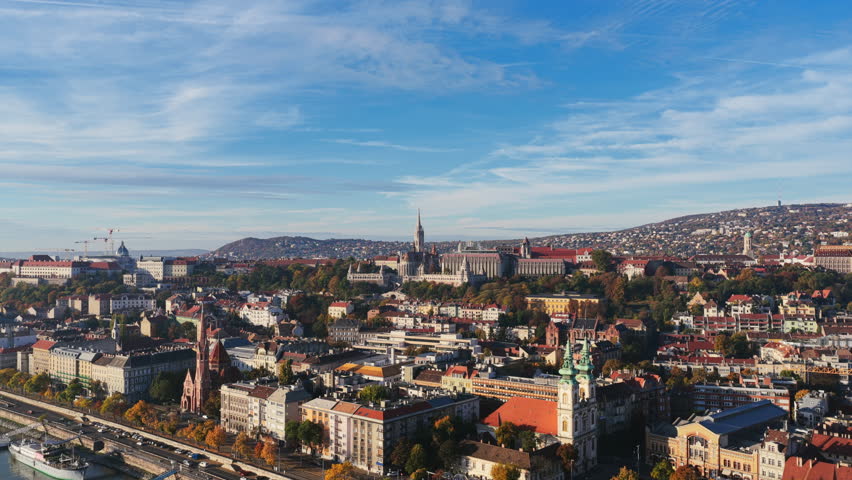 Budapest’s hilly Buda side with Matthias Church rising above the rooftops, framed by the city’s rolling hills and blue sky.