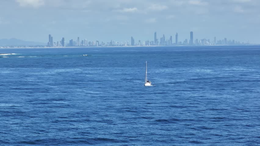 Daytime view of the Gold Coast skyline from Fingal Head with small sailing boat in the foregound, New South Wales, Australia