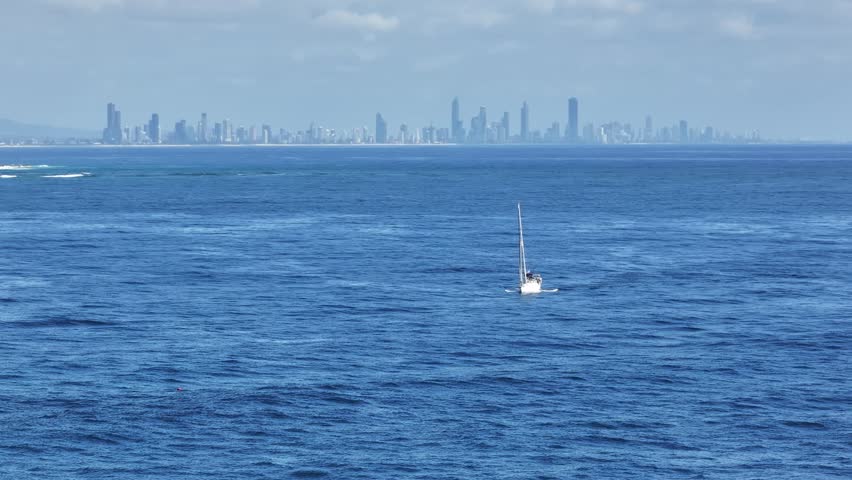 Daytime view of the Gold Coast skyline from Fingal Head with small sailing boat in the foregound, New South Wales, Australia