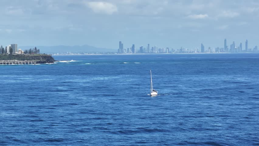 Daytime view of the Gold Coast skyline from Fingal Head with small sailing boat in the foregound, New South Wales, Australia