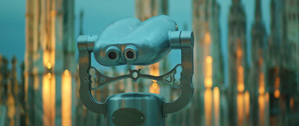 Binocular viewer facing illuminated spires on cathedral rooftop