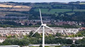 Large wind turbine spins steadily above suburban Dundee, Scotland, under bright daylight, static camera - Powered by Shutterstock - Get 15% off with code: PIKWIZARD15